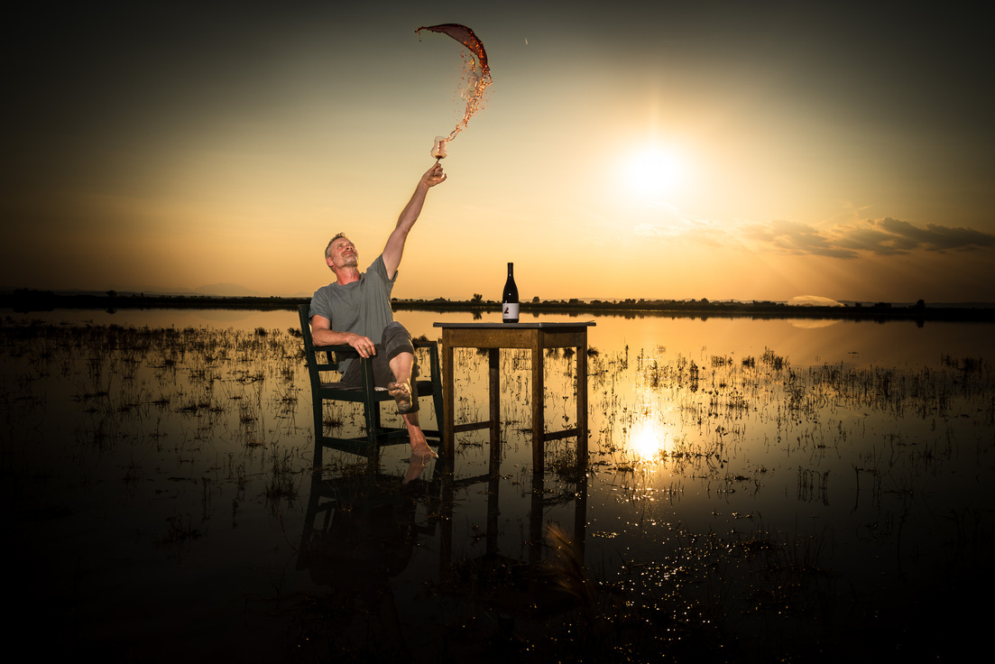 Der Winzer Georg Preisinger sitzt auf einem Stuhl im Wasser.